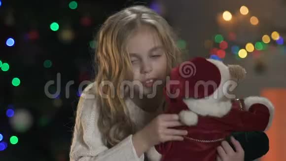 微笑的女孩紧紧拥抱毛绒熊等待圣诞节假期和礼物视频的预览图