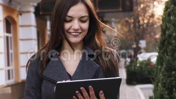 有魅力的年轻商务女性的特写肖像使用平板电脑户外微笑女孩在线购买视频的预览图