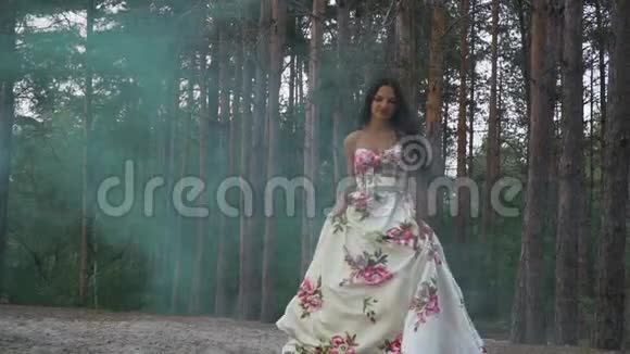穿着一件衣服的布鲁内特在森林的背景下走着带着彩色的烟雾视频的预览图