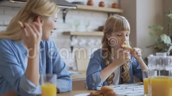 妈妈和女儿喝橙汁和饼干和松饼可爱的快乐家庭对话视频的预览图
