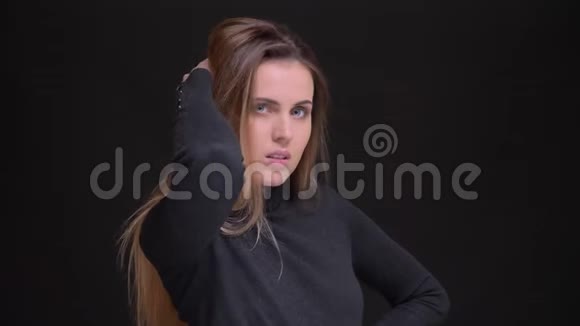 年轻的白种人长发金发女孩的肖像时尚地摆在黑色背景的相机上视频的预览图