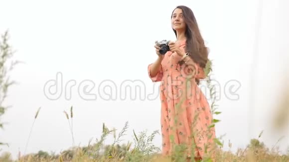 很漂亮的女孩手里拿着相机照片佩日慢动作草地上的田野视频的预览图