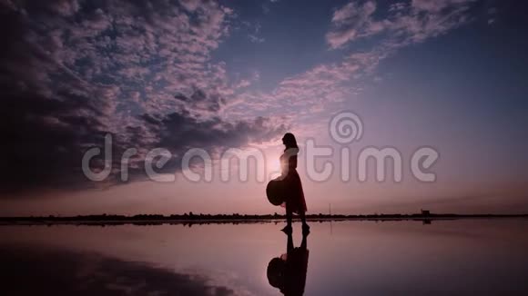 一个女人在夕阳背景下挥舞着裙子的剪影视频的预览图