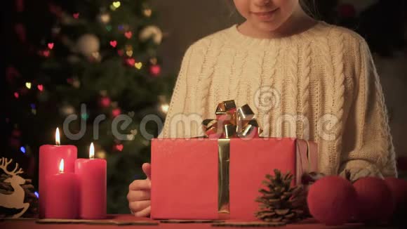快乐的女孩把圣诞礼物放在闪闪发光的树下准备惊喜视频的预览图