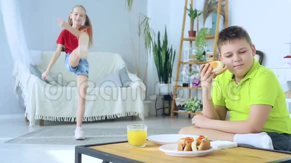 小男孩吃热狗的背景是一个正在做运动的女孩视频的预览图