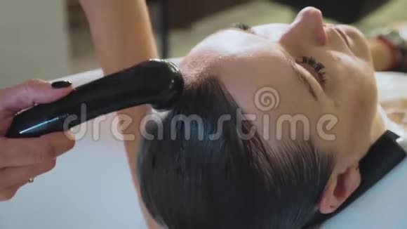 理发师在美容工作室里洗女人的头发视频的预览图