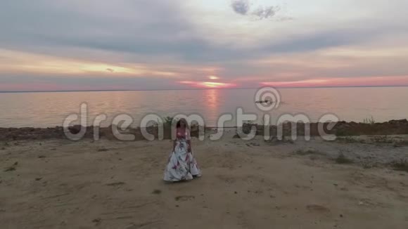 穿着长裙子的年轻女孩沿着海岸散步无人驾驶飞机中弹视频的预览图