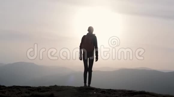 女人在夕阳的天空和山的背景上跳跃视频的预览图