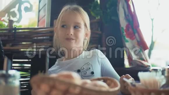 可爱的小女孩玩得开心坐在户外咖啡馆的桌子旁跳舞视频的预览图