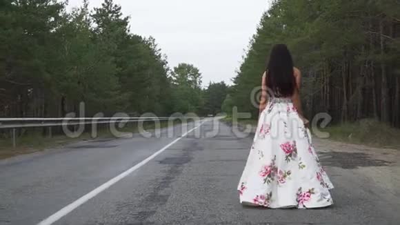 穿着一件漂亮长裙的漂亮女孩走在路上视频的预览图