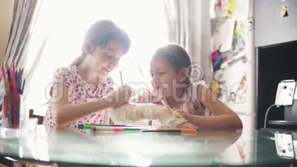 家庭护理理念孩子用绷带把她妹妹涂成灰的手画成鲜艳的颜色视频的预览图