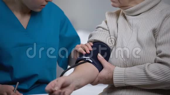 治疗师测量老妇人血压健康问题关闭视频的预览图
