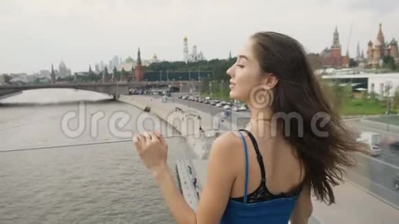 女孩黑发站特写桥河背景城市美丽的头发视频的预览图