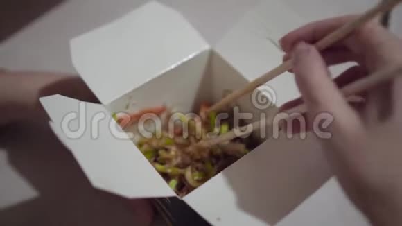 一个女孩在厨房里用筷子从盒子里吃炒面视频的预览图