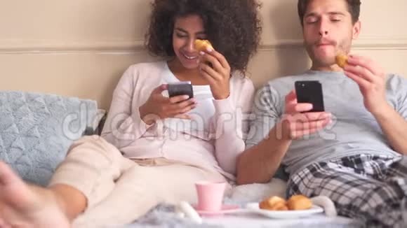 情侣在床上吃早餐时使用手机视频的预览图