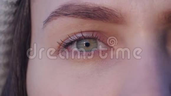 一个年轻迷人的女人的右绿色眼睛打开看着相机在日落时眨眼视频的预览图