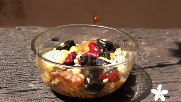 将糖浆倒入什锦豆和麦片中放入玻璃碗中视频的预览图
