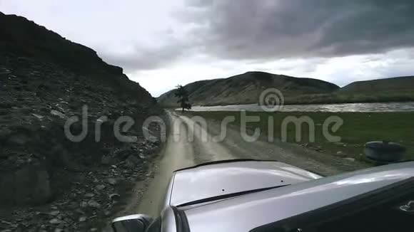 越野车骑在一条高山公路上越过一条山河汽车旅行一辆大汽车向前移动乡村离开这里视频的预览图