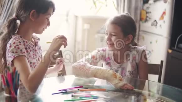 当她姐姐给她画一个石膏时一个胳膊断了的孩子笑了笑视频的预览图