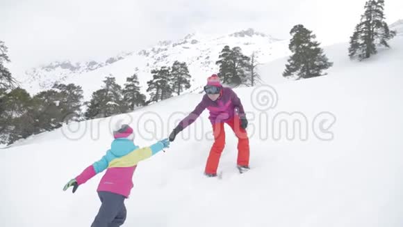 在母女之间帮忙两个徒步旅行者在山顶上一个女人帮助一个女孩爬雪视频的预览图