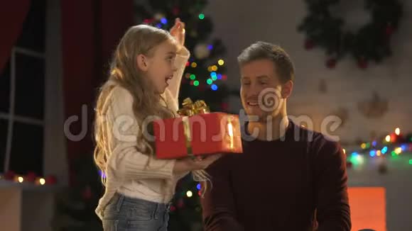 可爱的小女儿送给快乐的爸爸圣诞礼物灯光闪闪发光视频的预览图
