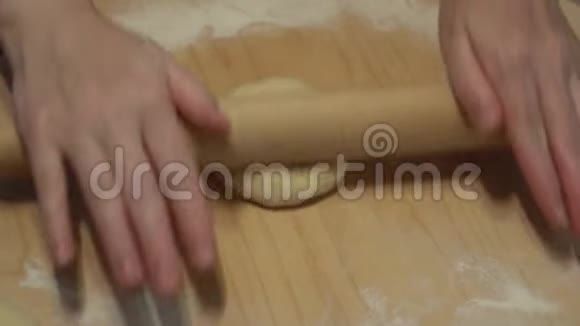 女人在板上滚动一个木制的擀面杖用面粉揉成面团做薄面团做披萨视频的预览图
