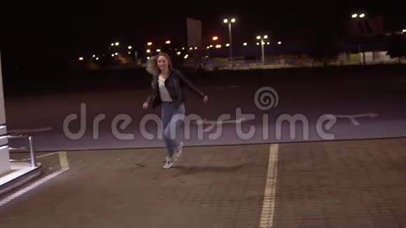 在加油站真正幸福的女人穿着牛仔裤和黑色皮夹克晚上到处跑视频的预览图