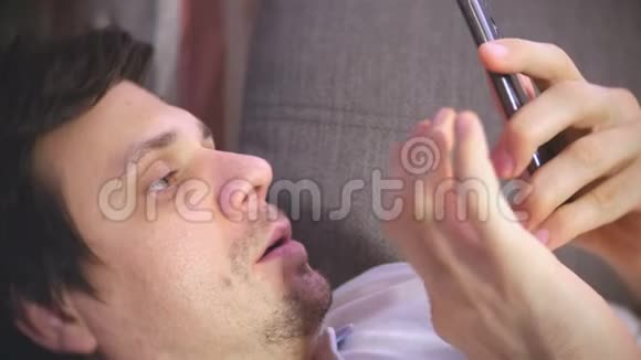 男人在躺在沙发上睡着的手机上输入一条信息视频的预览图