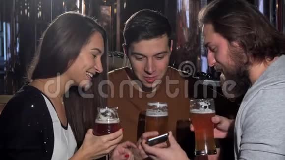 一群朋友在啤酒酒吧玩一起用智能手机视频的预览图