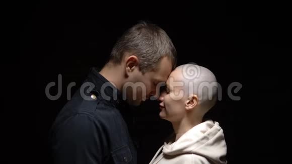 秃头的女人和她的丈夫在黑暗的背景下拥抱在一起复制空间视频的预览图