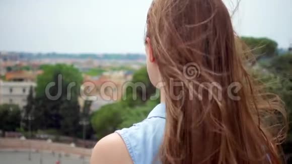 女人站在观景台上看城市全景女孩头发在风中缓慢地飘动视频的预览图