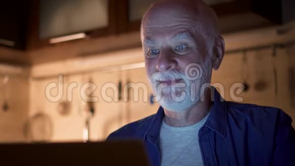 在家办公的老人通过晚上用笔记本电脑进行视频聊天与同事进行商务讨论视频的预览图