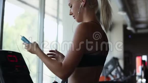 女运动员打开她的智能手机上的音乐改变速度水平上改变速度水平练习跑步近景视频的预览图