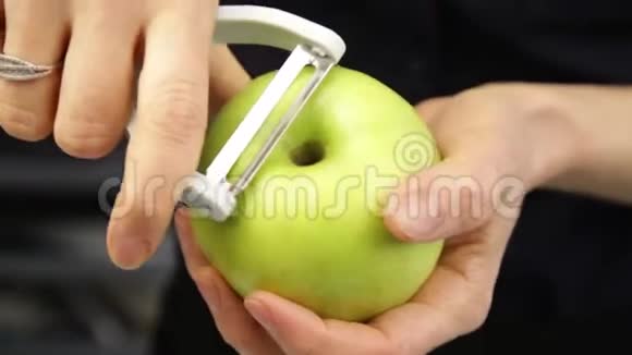 女人剥青苹果用专用刀关闭鲜苹果的工艺切皮健康食品视频的预览图