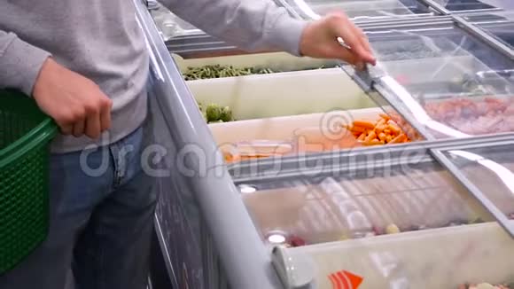 人在商场买胡萝卜一个年轻人拿起冷冻胡萝卜选择冷冻特写视频的预览图