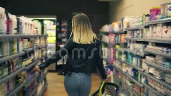 在超市里快乐的小女孩拿着购物篮在化妆品和奶制品上跳舞视频的预览图