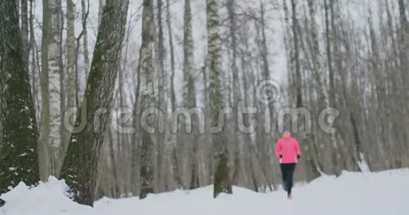 一个年轻的女人在冬天的森林里晨跑累了停下来休息继续跑他恢复了体力视频的预览图