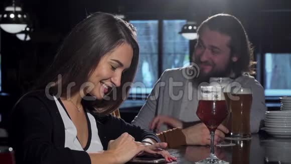 美丽快乐的女人用她的智能手机和朋友喝啤酒视频的预览图