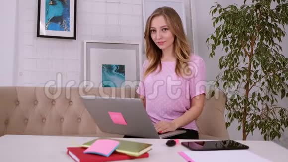 一个美丽迷人的女孩穿着一件粉红色的t恤金发碧眼看着摄像机在一个视频的预览图