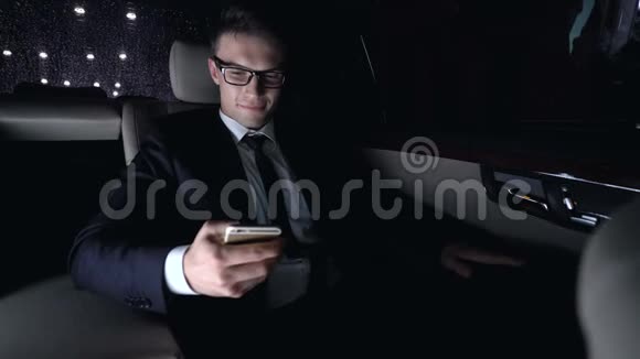 男西装革履跟女朋友在汽车后座发短信开车回家调情视频的预览图