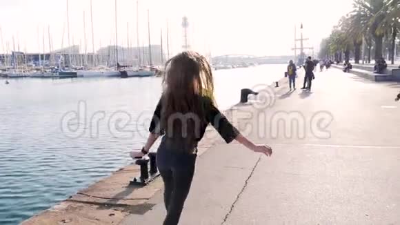 美丽的旅游女孩在海堤上跳舞手臂伸展在空中缓慢的有趣的金发少女视频的预览图