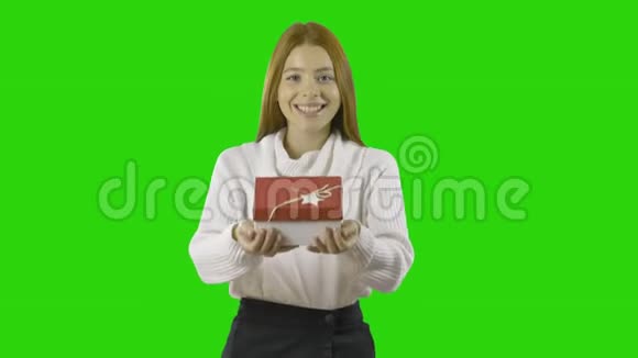 漂亮的女孩一头红色长发穿着白色毛衣手里拿着白色礼物带着丝带看着相机视频的预览图