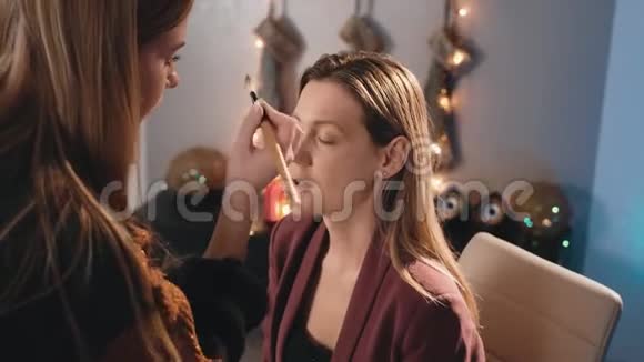 一个化妆师在一个白人金发模特的脸上用了一把刷子化妆生意的女人关于视频的预览图