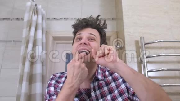 一个在浴室里宿醉的疯狂的被叫醒的男人用牙线把他的的牙齿弄掉视频的预览图