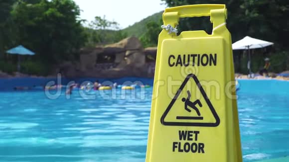 游乐园游泳池背景上黄色潮湿地板警示标志小心水上乐园的湿地板标志视频的预览图