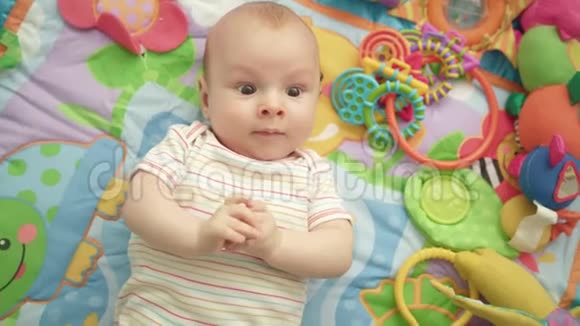 彩色地毯上的小男孩婴儿在垫子上放松的肖像视频的预览图