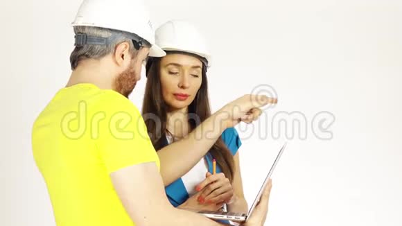 两个戴帽子的工程师或建筑师讨论项目并使用笔记本电脑视频的预览图