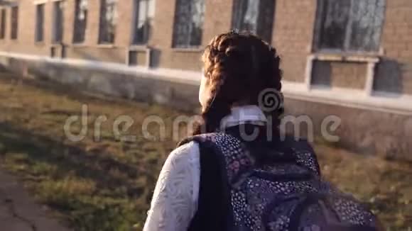 穿着校服的十几岁的女孩去学校和同学见面后景后方视频的预览图