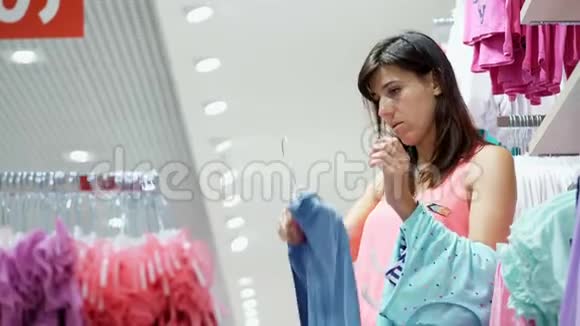 店里购物购物儿童服装部年轻的女人妈妈为她的孩子选择东西视频的预览图