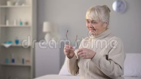 戴眼镜的微笑老年妇女看相册美好回忆家庭视频的预览图